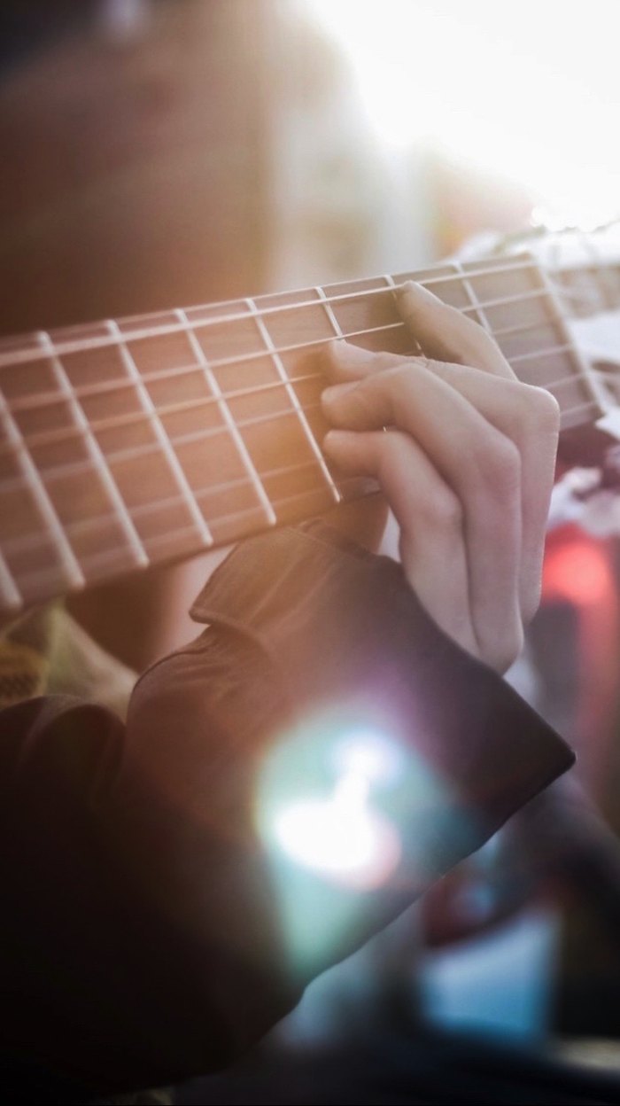Hands playing chords on an acoustic guitar